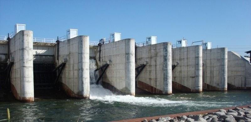 Presa de compuertas con agua descargando bajo una de ellas