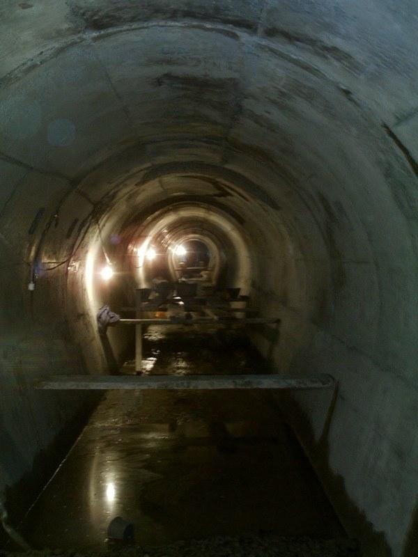 Túnel revestido de hormigón, iluminado, con agua en la solera
