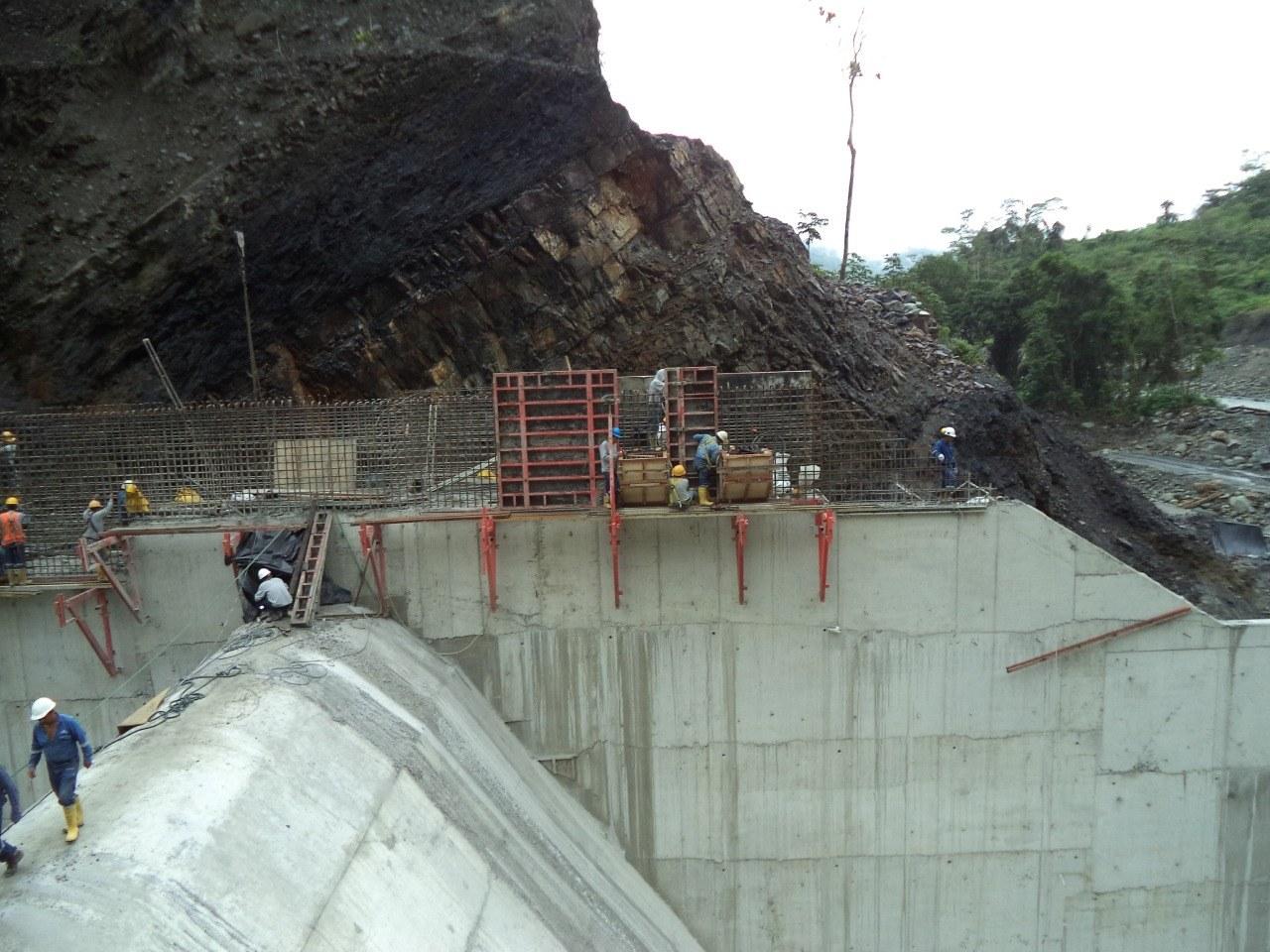 Encofrado y armadura sobre el muro de hormigón de la captación, al pie de una pared de roca